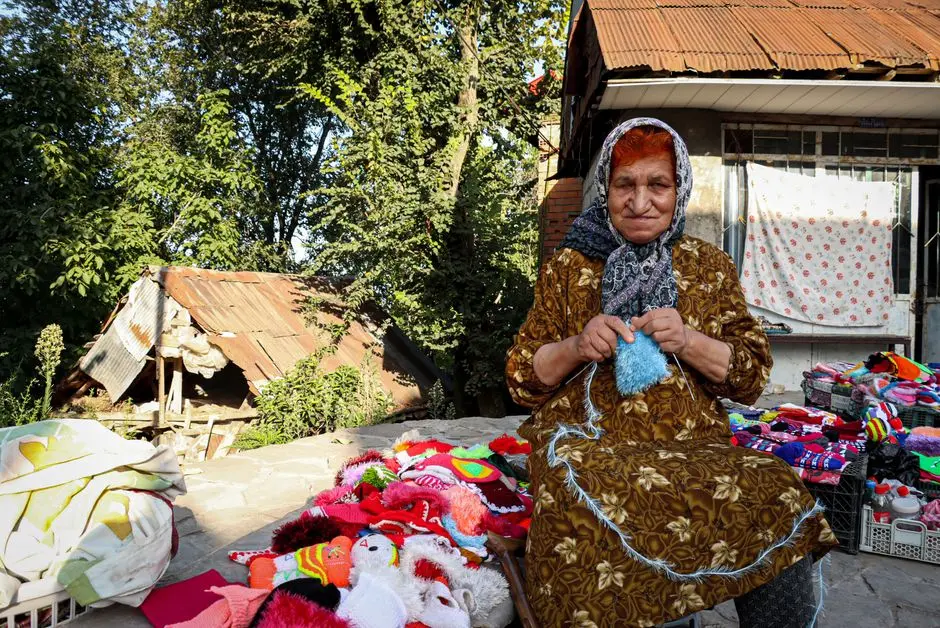 seorang wanita sedang merajut di teras rumah dengan pemandangan hijau